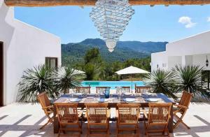 un patio con mesa de comedor y sillas y piscina en Villa Tauri Ibiza, en Nuestra Señora de Jesús