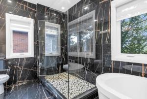 a bathroom with black tiled walls and a toilet andwindows at Welcome to Your Comfort Retreat by the Lake in Burlington +42 photos