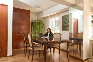 una mujer sentada en una mesa de comedor con un ordenador portátil en Hotel Park Suites Lima, Barranco, en Lima