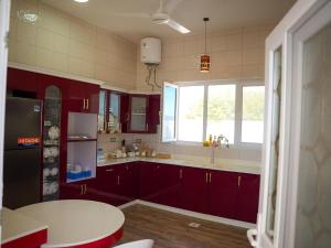 a kitchen with red cabinets and a table and a window at Beit Ward Al Jabal in Sayq