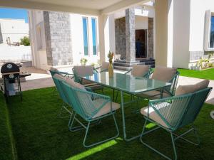 a glass table and chairs on a lawn at Beit Ward Al Jabal in Sayq
