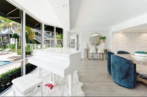 a white piano in a living room with a table and chairs at Boca Intercoastal Stay by Aureum, Pool, Gym, Walk to Beach in Boca Raton +42 photos