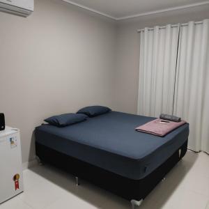 a bedroom with a bed with blue sheets and blue pillows at Refúgio Urbano in Ji-Paraná