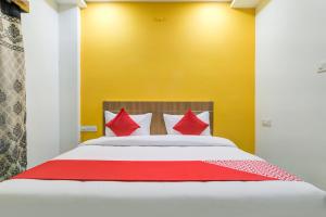 a bedroom with a bed with red pillows at Hotel O The Rudransh Inn in Indore