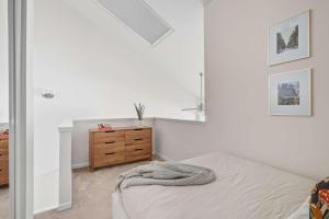 ポートランドにあるTrendy NW Portland Getaway - Walk to Dining & Barsの白いベッドルーム(ベッド1台、木製ドレッサー付)