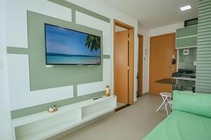 ein Wohnzimmer mit einem Flachbildfernseher an der Wand in der Unterkunft Flat Praia de Maracaípe - Porto de Galinhas in Porto De Galinhas