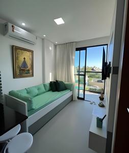 ein Wohnzimmer mit einem grünen Sofa und einem TV in der Unterkunft Flat Praia de Maracaípe - Porto de Galinhas in Porto De Galinhas + 31 Fotos