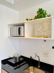 a kitchen with a sink and a microwave on a shelf at On Domingos By Bstay in Sao Paulo