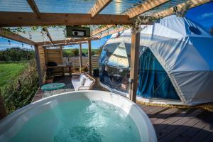 a hot tub on a deck with a tent at Coorie Retreats Luxury Geo Domes and Cabins with Private Hot Tubs Cinema Firepit Spa and More in Portpatrick