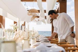 Ein Mann steht vor einem Tisch mit Geschirr. in der Unterkunft Naviva, A Four Seasons Resort, Punta Mita, Mexico in Punta Mita
