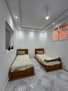two twin beds in a room with marble floors at Stylish Moroccan Apartment in Marrakesh