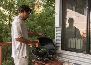 a man is cooking food on a grill at Tallaringa Views in Alstonville