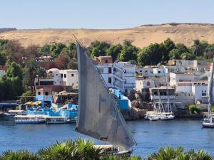 un velero en un cuerpo de agua con edificios en Pajama Hostel Nile View, en Asuán