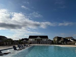 a swimming pool with lounge chairs in front of a house at Spacious 4BR Oasis - Pool - Patio - 8 Min to Kalahari in Round Rock
