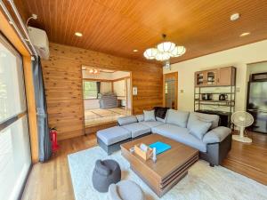 a living room with a couch and a table at Frolic Field Nasu 源泉温泉の檜風呂 一棟貸切 BBQ ドッグラン 犬OK 9名 星空テラス in Nasu +64 photos