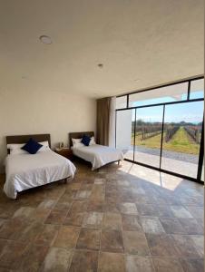 two beds in a room with a large window at Casa Diamante Viñedos in Ezequiel Montes