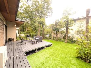 a backyard with a wooden deck with a table and chairs at Frolic Field Nasu 源泉温泉の檜風呂 一棟貸切 BBQ ドッグラン 犬OK 9名 星空テラス in Nasu