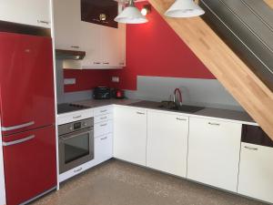 a kitchen with white cabinets and a red wall at Gîte au Calme Proche de Nancy avec Terrasse Privative et Parking - FR-1-584-103 in Champenoux