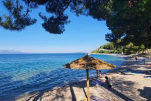 a beach with an umbrella and people on the beach at Apartment Podaca 4734b in Podaca +15 photos