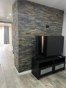 a living room with a tv on a brick wall at Charming Aldershot Home - Free Parking in Ash