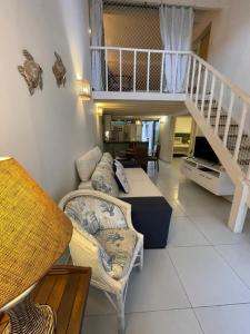 a living room with a couch and a staircase at Casa- Maresias 3 minutos da praia in Maresias