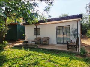 une maison avec un banc et une table dans une cour dans l'établissement The Silken Oak, à Kasama