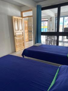 two beds in a room with a window and a door at Casa Garden in San Pedro La Laguna +2 photos