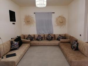 a living room with a brown couch with pillows at Ferme d'hôtes Aghbalou in Sefrou