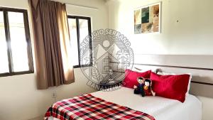 two dolls sitting on top of a bed with red pillows at Refúgio Serrano Bananeiras in Bananeiras +59 photos