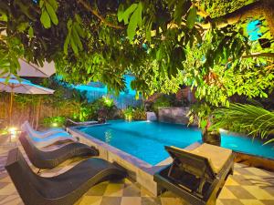 a swimming pool in a garden with chairs around it at Angkor Rise Residence in Siem Reap