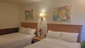 two beds in a hotel room with paintings on the wall at Beltway Motel and Suites in Halethorpe