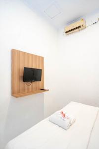 ジャカルタにあるTamastu House Pasar Baru Jakartaの壁にテレビとベッドが備わる客室です。