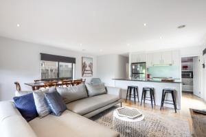 a living room with a couch and a kitchen at Stylish Coastal Retreat in Ocean Grove