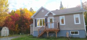 a house with a deck on the side of it at Coin cosy dans les bois in Sainte Brigitte de Laval