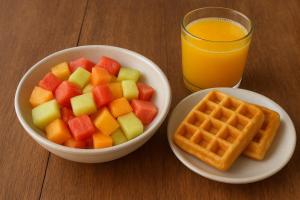 a bowl of fruit and waffles and a glass of orange juice at Hotel MONARCA in Jamundí