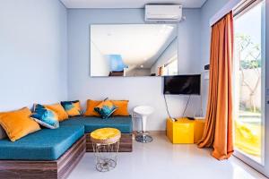 ein Wohnzimmer mit einem blauen Sofa und orangefarbenen Kissen in der Unterkunft 2BR Sun Flower Home in Uluwatu