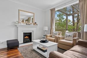 a living room with a couch and a fireplace at Villa Piccola Casa, Premier 2 Storey Villa, 2 Bedrooms, both with private ensuites, with third toilet on the ground floor in Pokolbin