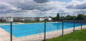 a large swimming pool behind a fence at Tiny Beach Cottage - New Vennepark Wenduine in De Haan
