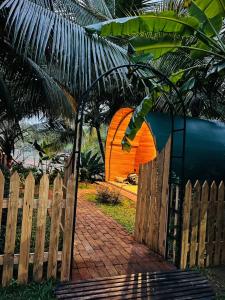 une tente orange se trouve derrière une clôture en bois dans l'établissement Garden Oasis Rekawa, à Rekawa
