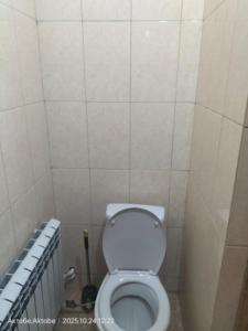 Un baño con un inodoro blanco en una cabina. en Хостел Москва, en Aktobe