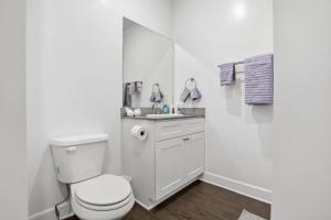 a white bathroom with a toilet and a mirror at Relax and Explore Poolside Stay Near Local Spots in Sunny Acres