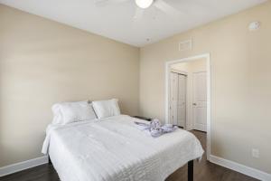 a white bedroom with a bed and a ceiling fan at Relax and Explore Poolside Stay Near Local Spots in Sunny Acres