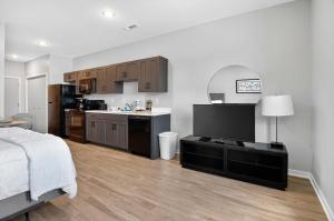 a room with a bed and a kitchen with a television at Stylish Downtown Escape Near IU and Cafes in Bloomington +29 photos