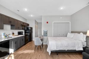 Un dormitorio con una cama blanca y una cocina. en Stylish Downtown Escape Near IU and Cafes, en Bloomington