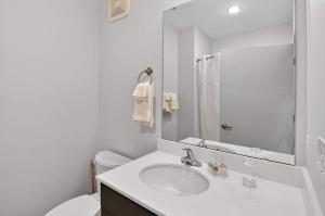 Un baño blanco con lavabo e inodoro. en Stylish Downtown Escape Near IU and Cafes, en Bloomington