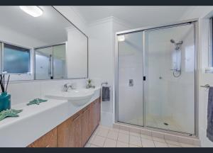 een badkamer met een glazen douche en een wastafel bij Ocean Aura Room A in Airlie Beach
