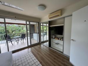 een woonkamer met televisie en een balkon bij Ocean Aura Room A in Airlie Beach