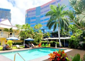 a pool at a hotel with palm trees and a building at Bposhtels Waikiki Retreat in Honolulu