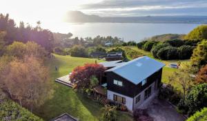 an aerial view of a house on a hill next to the water at Stunning panoramic Lakeview , spa pool & privacy in Taupo