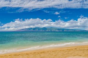 a view of the beach with mountains in the background at Oceanfront Kahana Condo Ocean View, Beachfront, Pool & Sleeps 4, Walkable Area in Lahaina